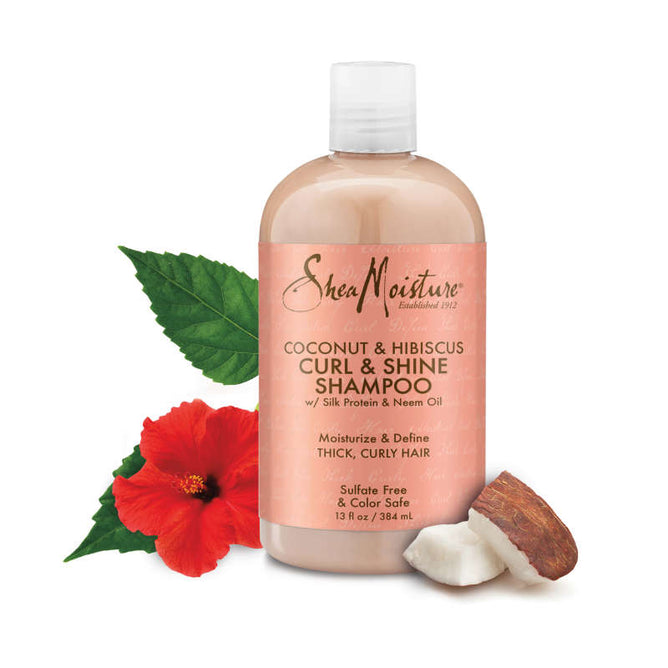 A 13 fl oz (384 ml) bottle of SheaMoistures Coconut + Hibiscus Curl & Shine Shampoo for curly hair is shown with a red hibiscus, coconut piece, and neem leaves, showcasing its nourishing label.