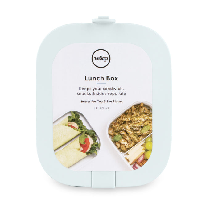 The W&P Reusable Bento Box (VIP Discount) in light blue has two compartments—one for a wrap and salad, the other for pasta and grapes—keeping foods separate in a portable, square lunch box.