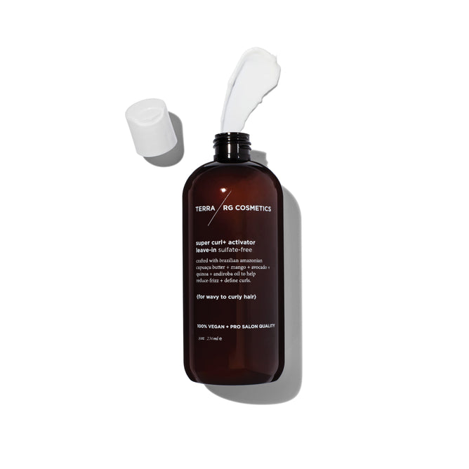 A brown bottle of Terra Beauty Bars Curl+ Activator Curl Leave-In with frizz protection lies on its side, its detached white cap nearby. White cream enriched with Brazilian superfoods spills from the open top, casting a shadow. Text on the bottle highlights the products features.