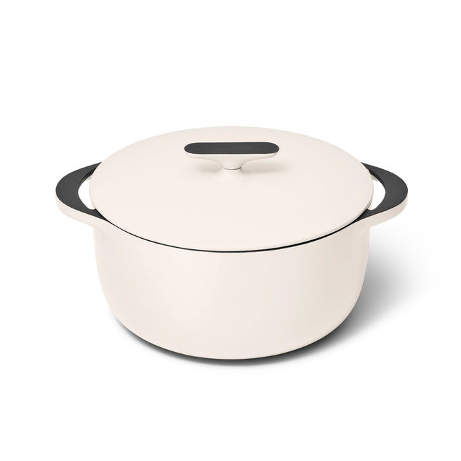 Caraways 6.5 qt Cast Iron Dutch Oven with Flat Lid is a sleek, white enameled pot featuring black handles and lid, offering superior heat retention while sitting elegantly against a plain white background.