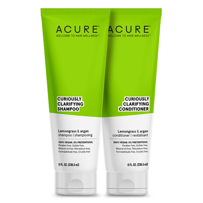 Two tubes of Acures Curiously Clarifying Shampoo and Conditioner Set, featuring white and green design, stand side by side. Each 8 fl oz (236.5 ml) tube delivers gentle cleansing with lemongrass and argan oil for refreshing care, enhanced with organic oils.