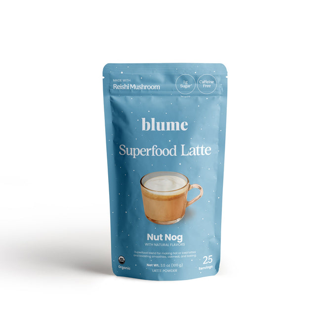 Blumes Nut Nog Blend boasts festive blue and white packaging, with a mug illustration filled with frothy goodness. It highlights Made with Reishi Mushroom, No Sugar, Caffeine Free, Organic, and Vegan Nut Nog. Each 100g pack offers 25 servings of holiday cheer.