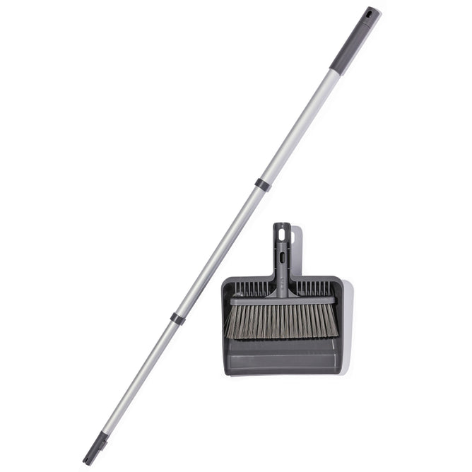 The Grove Co. Compact Broom and dustpan set, crafted in gray, features dust-collecting bristles and a long detachable handle. The dustpan includes a built-in holder, and both are designed using recycled materials for sustainable floor cleaning.