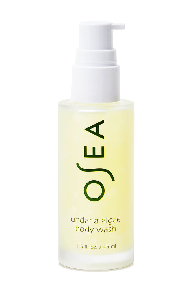The 1.5 fl. oz. travel-sized bottle of OSEA Undaria Algae™ Body Wash, featuring a clear design with a white pump, displays OSEA and product details in green text. It highlights its pH-balanced formula and signature Undaria Algae Body Oil scent.