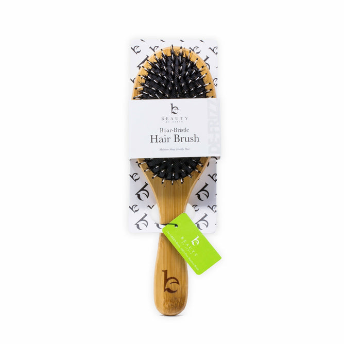 The Beauty by Earth Boar Bristle Hair Brush has a wooden handle, comes on a branded black and white cardboard backing, and includes an eco-friendly green tag with the logo.