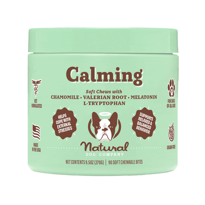 A 90-chew green container of Calming Dog Supplement Soft Chews by Natural Dog Company, flavored with Peanut Butter & Bacon, includes natural calming elements like chamomile, valerian root, and melatonin to ease stress and support balanced behavior. Made in the USA.