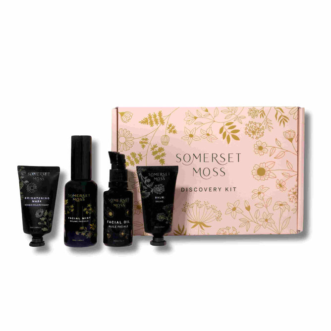 The Somerset Moss Discovery Kit, in a pink floral box, boosts skin confidence with a rejuvenating cream, facial mist, oil, and balm. Each dark container flaunts botanical designs and promises anti-ageing benefits.