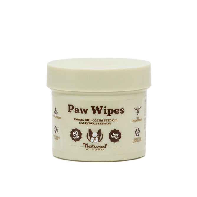 Natural Dog Companys Paw Wipes come in a beige container with 50 wipes enriched with jojoba oil, cocoa seed oil, and calendula extract for natural moisturizing. Perfect for keeping your dogs paws clean and nourished.