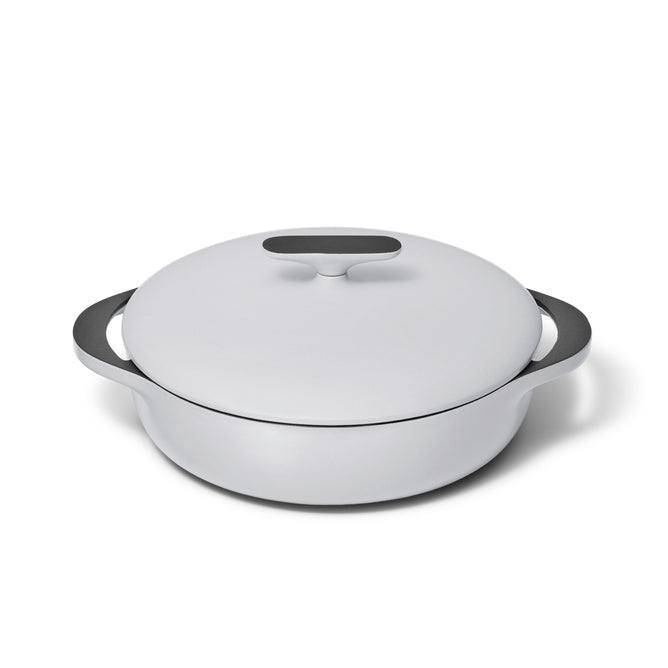 The Caraway Cast Iron Braiser with Lid, 3.5 qt, is a white enameled dish featuring rounded handles and a flat handle on the lid. It offers superior heat retention with a sleek, modern design and smooth glossy finish.
