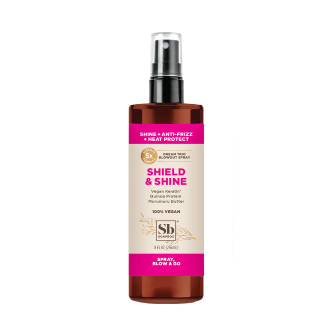 The Shield & Shine Blowout Spray by Soapbox features anti-frizz, shine-enhancing qualities with vegan keratin, quinoa protein, and murumuru butter. It comes in a brown bottle with a black spray top and striking pink accents.