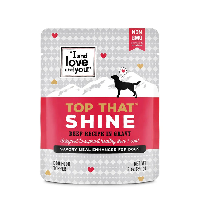The Top That Shine Beef Recipe in Gravy by I and Love and You is a delightful wet dog food topper with a mountain backdrop, heart design, and dog silhouette. The label highlights Non GMO, Meal Enhancer, and net weight of 3 ounces (85g).