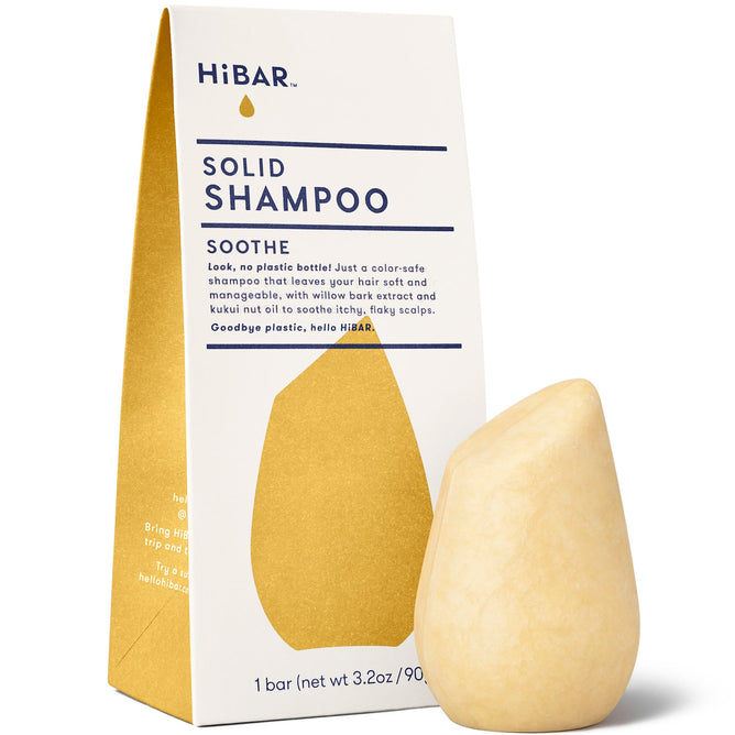 A HiBAR Soothe Shampoo Bar sits beside packaging labeled HiBAR Solid Shampoo Soothe, highlighting a color-safe formula with willow bark extract. Ideal for dandruff-prone skin, the beige, teardrop-shaped bar contains natural ingredients for gentle cleansing.