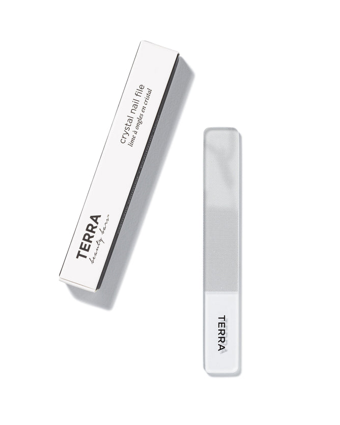 The Crystal Nail File by Terra Beauty Bars, with nano glass tech, comes in a white rectangular package labeled TERRA beauty bars. This recyclable nail file guarantees a lifetime of smooth edges and features a clear design with a frosted tip.