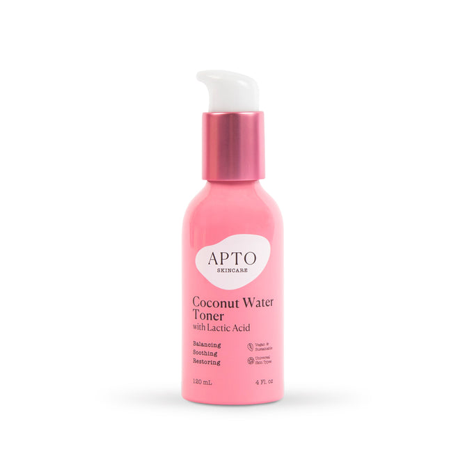A pink 120 ml (4 fl oz) bottle of APTO Skincare Coconut Water Toner with Lactic Acid and electrolytes features a white pump top. This cruelty-free toner balances, soothes, and restores for a luminous complexion.