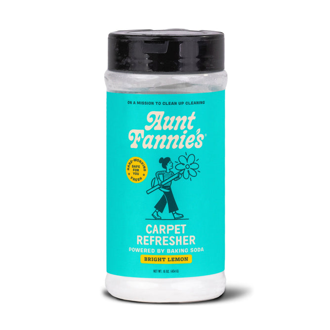 Aunt Fannies Carpet Refresher, ideal for clean carpets, has a bright teal label featuring a person with a flower. The text reads Powered by Baking Soda and Bright Lemon. It is topped with a black lid.