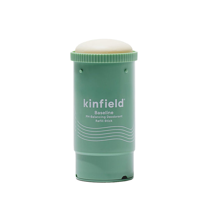 Green cylindrical Kinfield Baseline Deodorant - Refill features a twist mechanism, rounded cap, and recyclable packaging. The label highlights pH-balancing fruit enzymes in white text on a plain background.