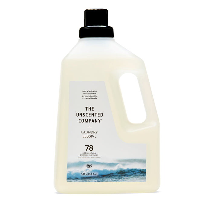 A plastic jug of The Unscented Companys concentrated laundry detergent, offering 78 washes. Featuring ocean waves on the label, the light beige bottle with a black cap has a built-in handle for easy pouring and is crafted with naturally derived ingredients.