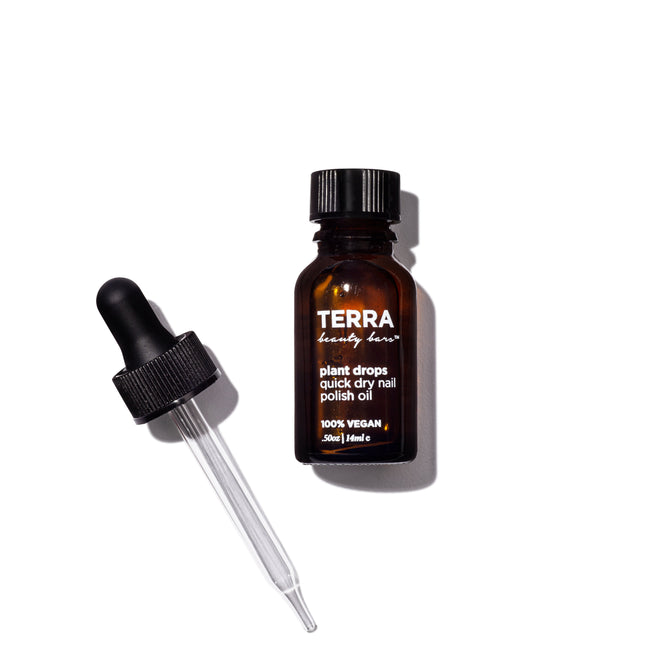 A 15 ml dark amber glass bottle labeled Terra Beauty Bars contains Plant Quick Dry Nail Polish Oil. It features a black screw cap and matching dropper for swift application of the 100% vegan formula. The sleek design is set stylishly against a white background.