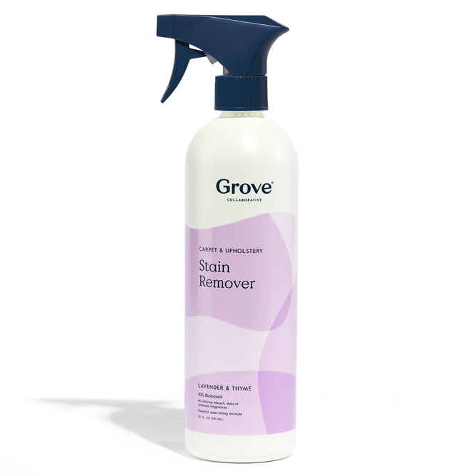 A Grove Co. Carpet & Upholstery Stain Remover spray bottle features a purple abstract design, a Lavender & Thyme scent, and a navy blue nozzle. This plant-based cleaner tackles tough stains gently.