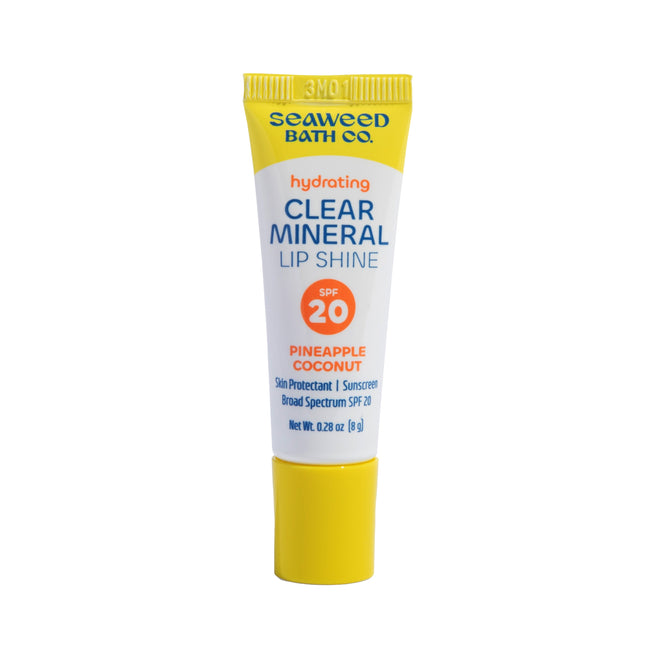 A yellow tube of The Seaweed Bath Cos Clear Mineral Lip Shine in Pineapple Coconut delivers ultra-nourishing care with a glossy finish, featuring a mineral SPF 20 lip balm formula for broad spectrum protection. Net weight: 0.28 oz (8g).