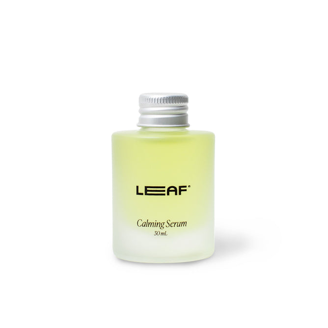A small, frosted transparent bottle labeled Calming Serum Refill 30 mL, by Leaf Shave, contains a light green liquid enriched with essential oils. Topped with a silver screw cap, it exudes tranquility against a plain white background.