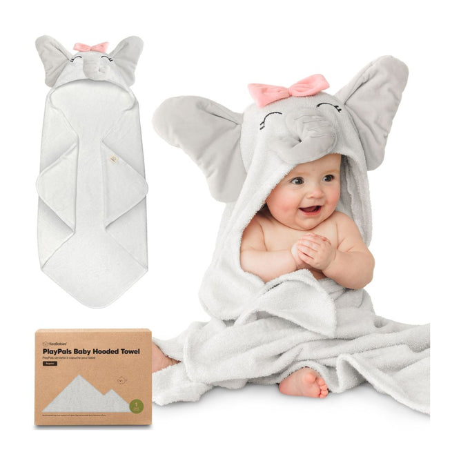 A smiling baby sits wrapped in a soft, gray elephant hooded towel with large ears and a pink bow. Next to the baby is an unfolded sustainable KeaBabies towel. The GOTS Certified, 100% Organic Cotton Hooded Towel packaging is nearby.