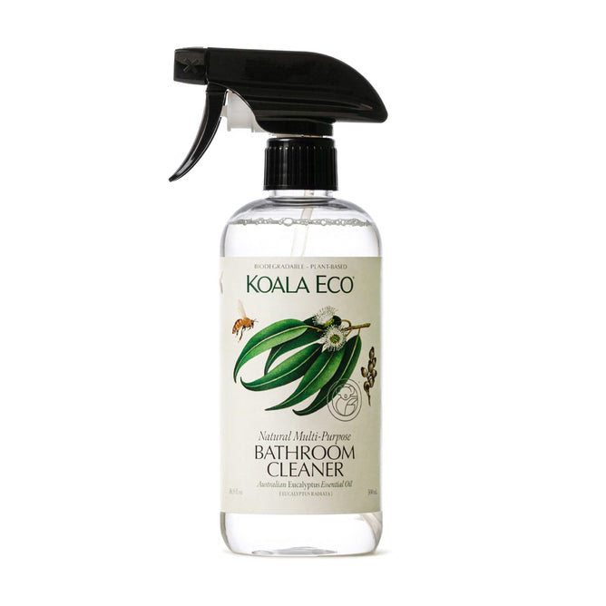 The transparent bottle of Koala Eco Natural Multi-Purpose Bathroom Cleaner, with a black spray nozzle, contains clear liquid. The label features eucalyptus leaves and flowers, reflecting its Eucalyptus Essential Oil essence. This plant-based cleaner is biodegradable and effective against bacteria.