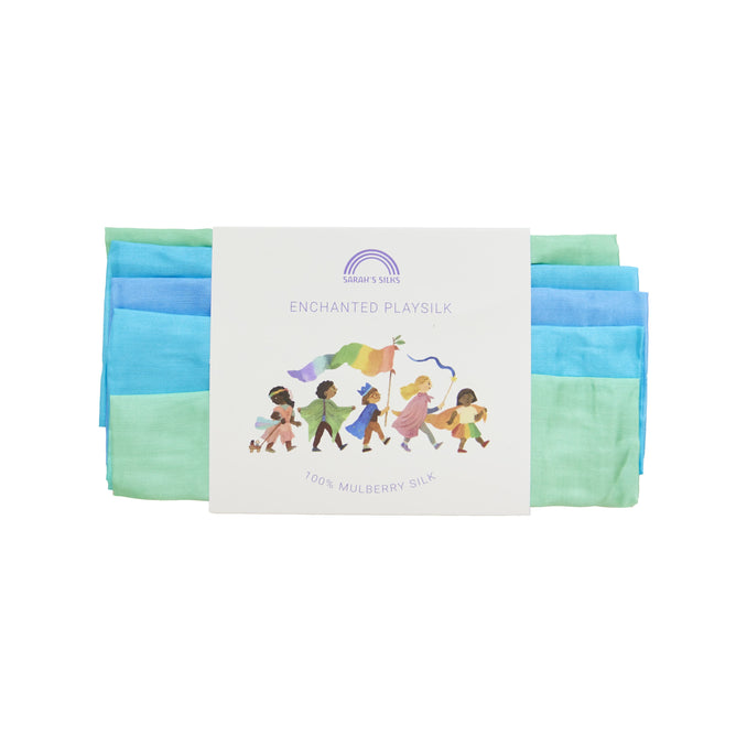 Sarahs Silks Enchanted Playsilk is a vibrant blue and green set of 100% Mulberry Silk, ideal for Montessori & Waldorf homes. Packaged with diverse children illustrated holding a rainbow silk banner, its perfect for open-ended play and features a rainbow logo on the label.