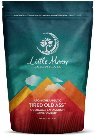 Little Moon Essentials Tired Old Ass mineral bath salt comes in a colorful, resealable pouch featuring a mountain design. Infused with essential oils, it offers an effortless way to combat exhaustion.
