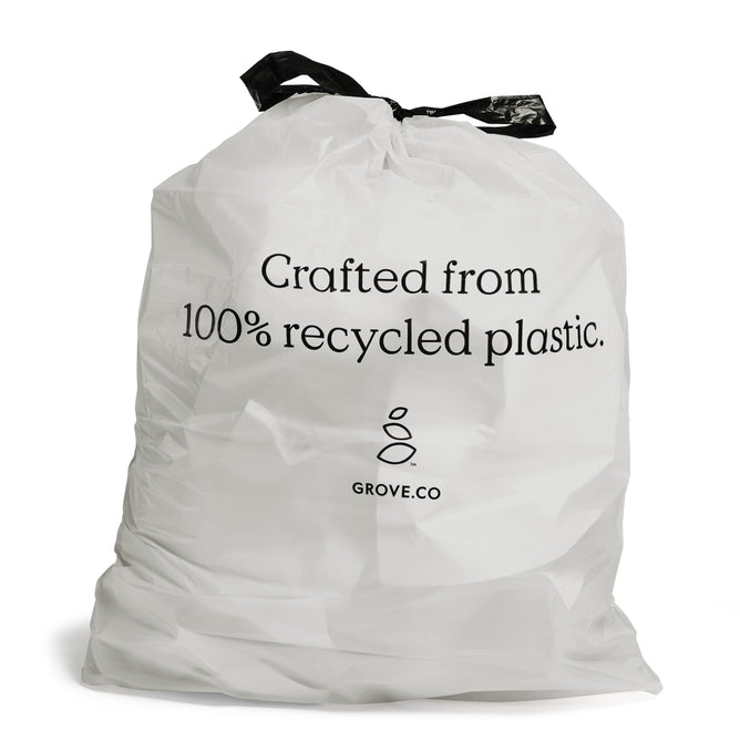 A crumpled white 13-gallon trash bag by Grove Co., features black drawstring handles and text stating Crafted from 100% recycled plastic. Below the text is a logo with two leaf-like shapes and GROVE.CO wording.