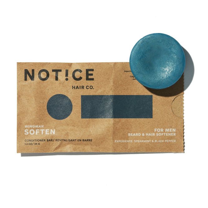 A brown paper package labeled NOT!CE Hair Co. features a blue Soften Conditioner Bar for mens beard and hair, scented with spearmint and black pepper. It highlights sustainable self-care through plastic-free hair care, reading “WINGMAN SOFTEN.”.