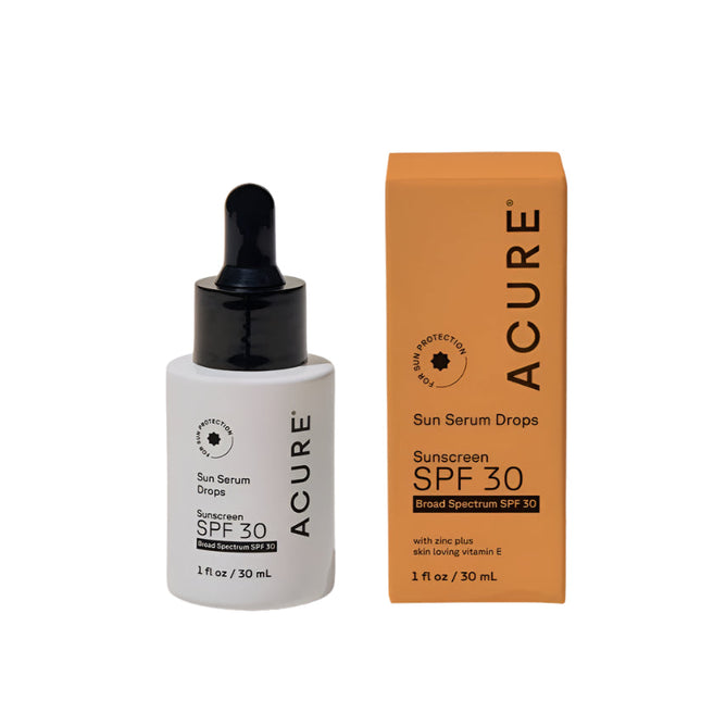A white dropper bottle of Acure Sun Serum Drops SPF 30, enriched with hydrating serum and vitamin E, stands beside its orange box on a white background. Both feature the Acure branding and clear SPF 30 labeling.