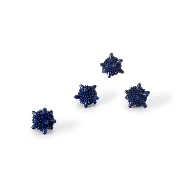 Four Agitator Washer/Dryer Balls by Esembly Baby, with a spiky texture in dark blue, are evenly spaced on a plain white background.