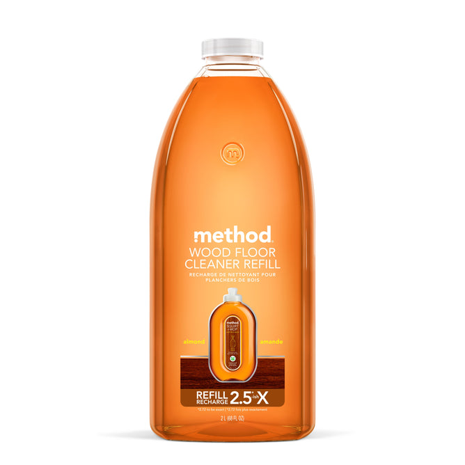 Displayed is a Method Squirt Mop Wood Floor Cleaner Refill in recycled plastic. The almond-scented cleaners orange label with white text indicates it contains 2.5 times more than the standard size, ideal for your cleaning needs.