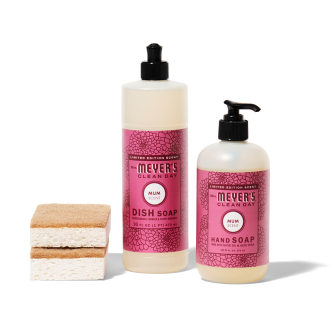 The crisp-clean-sinkside-set from Grove Collaborative includes two Mrs. Meyers Clean Day soaps with pink mum scent labels and black pumps: a 16 fl oz dish soap and a 12.5 fl oz hand soap. Two stacked sponges are on the left of the bottles.