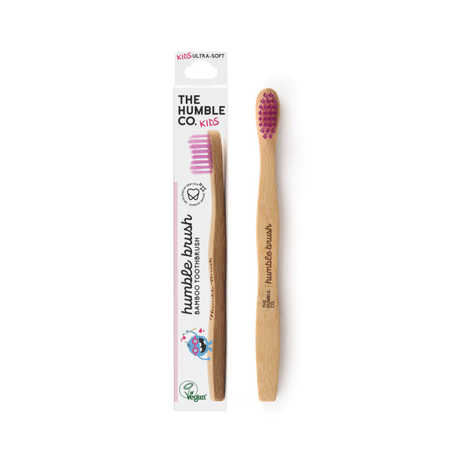 A Kids Bamboo Toothbrush - Ultra Soft by The Humble Co., featuring nylon bristles with pink tips, is shown next to its packaging. It displays a cartoon character and highlights features like Ultra-Soft and Vegan.