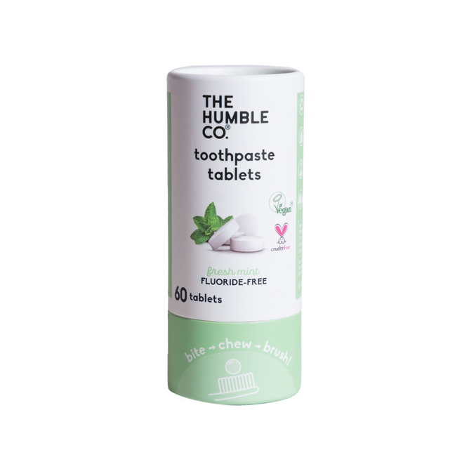 A cylindrical container of The Humble Co. Flouride Free Dental Tabs includes 60 fresh mint tablets, vegan and cruelty-free. Designed for eco-conscious travelers, the green and white packaging features tooth icons.
