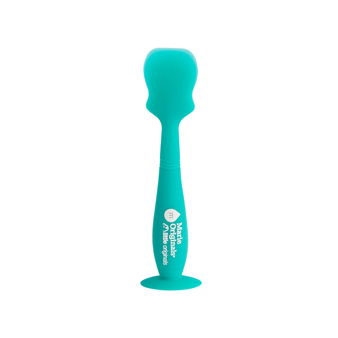 The Marie Originals Diaper Spatula features a teal silicone spoon with a bulbous head, curved handle, and a suction cup base for hygienic storage. The handle displays white text and a symbol. Its designed to resemble a diaper spatula and set against a plain white background.