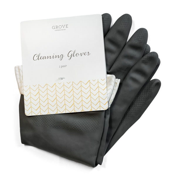 A pair of black cleaning gloves is partially covered by a white cardboard label with gold chevron patterns. The label reads Grove Co. and Cleaning Gloves, 1 pair. These durable latex gloves have textured fingertips and a soft lining inside.