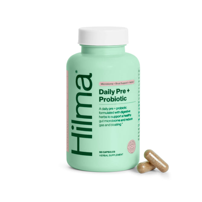 The Hilma Pre + Probiotic dietary supplement, in a green bottle with 60 capsules, supports gut health. Two capsules next to the bottle highlight its role in digestive wellness.