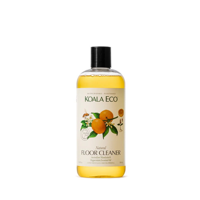 A clear Koala Eco Natural Floor Cleaner bottle displays orange liquid, with a label featuring oranges and leaves. It emphasizes Australian essential oils and natural ingredients, completed by a black cap for this eco-friendly solution.