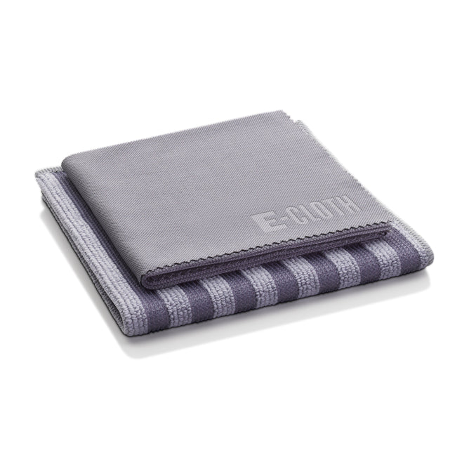 A neatly folded stack of two towels—one solid gray and the other gray with dark stripes. The top towel, part of the E-Cloth Stainless Steel Cleaning Kit, features an embossed logo. Both towels appear soft and luxurious.