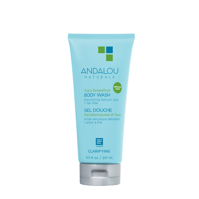 The blue 8.5 fl oz (251 ml) tube of Andalou Naturals Clarifying Yuzu Grapefruit Body Wash contains detoxifying salicylic acid and tea tree, with a bilingual English-French label highlighting its commitment to clean skincare.