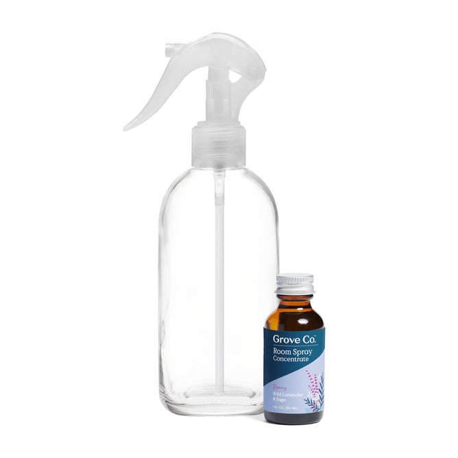 A clear spray bottle is placed next to a small amber bottle labeled Grove Collaborative Room Spray Concentrate, featuring a lavender design, containing 0.68 fl oz (20 ml) of liquid from the room-spray-bottle-and-concentrate-set.