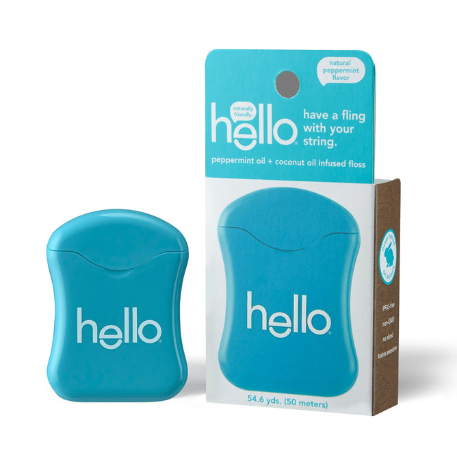 A blue container of hello Peppermint Floss, enriched with coconut oil, is next to its white and brown packaging that emphasizes the natural peppermint flavor and cruelty-free floss, totaling 54.6 yards (50 meters).