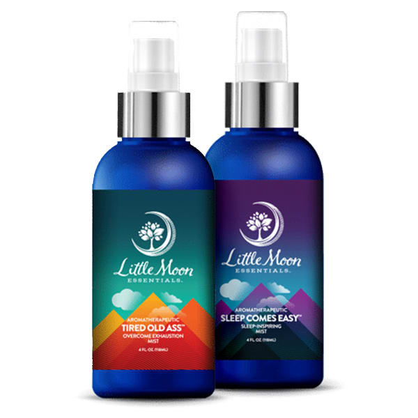 The Essential Mist Duo from Little Moon Essentials features two spray bottles: Tired Old Ass mist with a colorful mountain design and Sleep Comes Easy in a calming blue and purple palette. Both contain essential oils and feature a round logo on top, showcasing the best in aromatherapy.