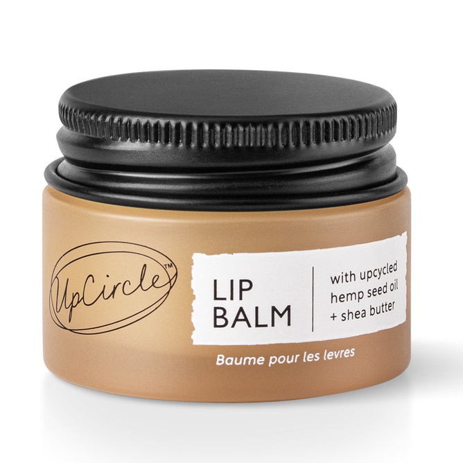 A small tan jar with a black screw-on lid sports the label UpCircle Lip Balm with Hemp Seed Oil and Shea Butter, with text in English and French.