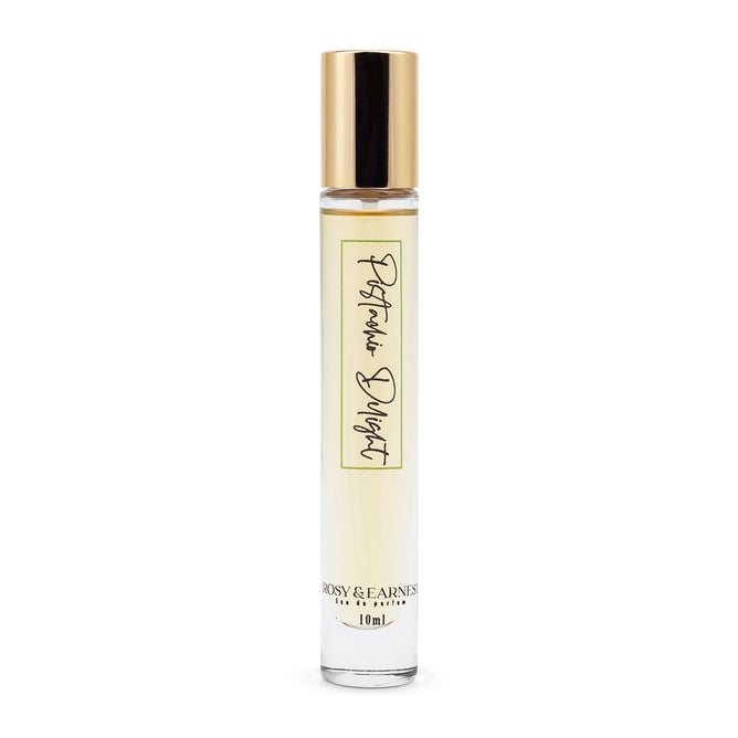 A small, transparent 10ml bottle with a gold cap and yellowish liquid inside reads Pistachio Delight on the label, hinting at its gourmand fragrance. The brand Rosy & Earnest graces the bottom, showcasing a simple, elegant design for an olfactory delight.