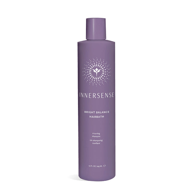 A tall, cylindrical purple bottle labeled Bright Balance Hairbath by Innersense Organic Beauty, featuring a stylized sunburst design. This vegan violet shampoo neutralizes brass tones, set against a plain white background.