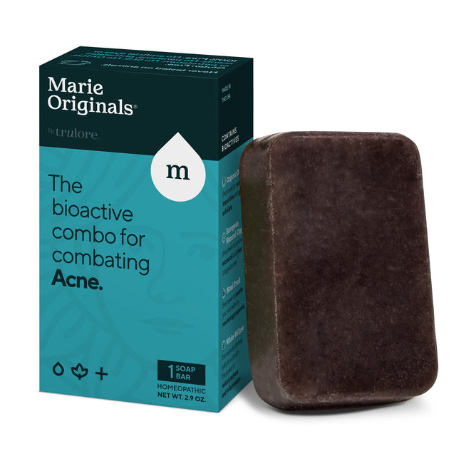Marie Originals Acne Control Soap sits next to its teal and black box labeled, The bioactive combo for combating Acne. It features bentonite clay for natural treatment, with symbols of water, a drop, and a plus sign on the packaging.